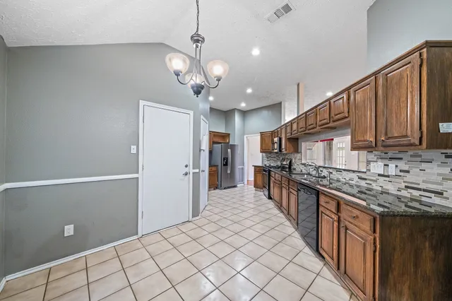 a kitchen with stainless steel appliances granite countertop a refrigerator and a stove top oven