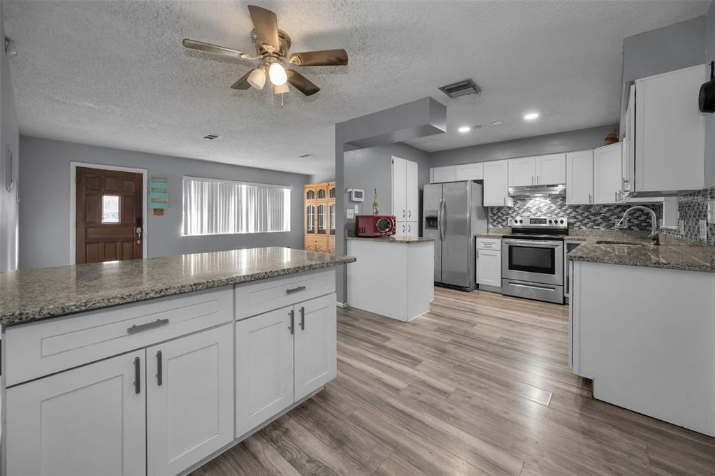 14557 Apache Avenue Largo, FL 33774 - Photo 36 of 51 a kitchen with stainless steel appliances kitchen island granite countertop a stove and cabinets