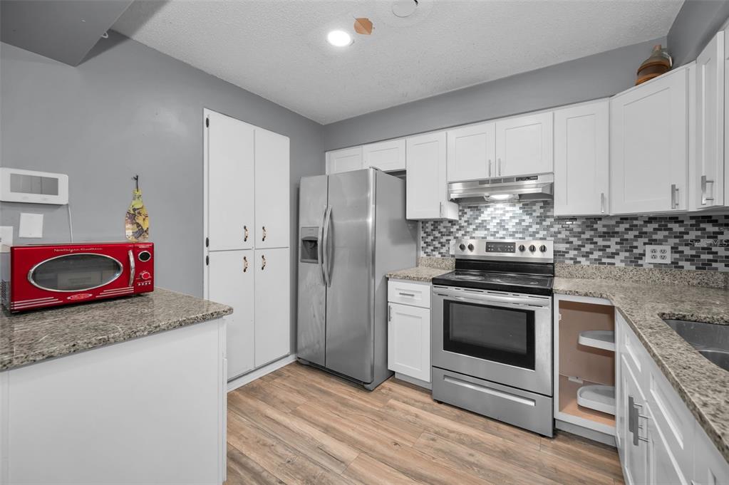 14557 Apache Avenue Largo, FL 33774 - Photo 10 of 50 a kitchen with stainless steel appliances granite countertop a stove a refrigerator and a sink