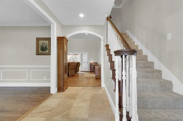a view of a hallway to a livingroom with wooden floor and stairs