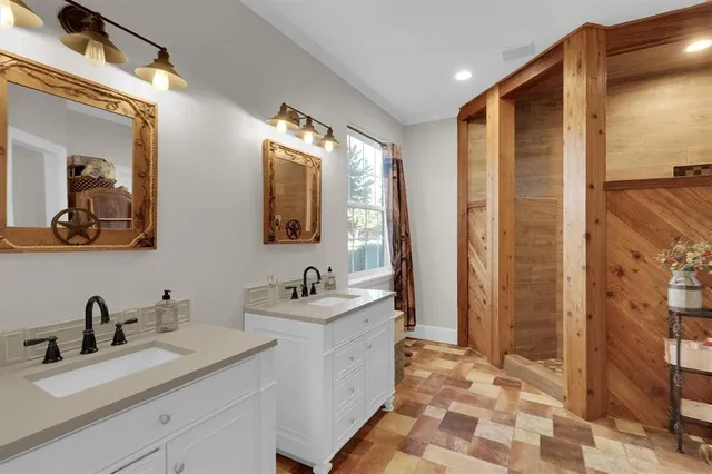 a bathroom with a double vanity sink mirror and shower