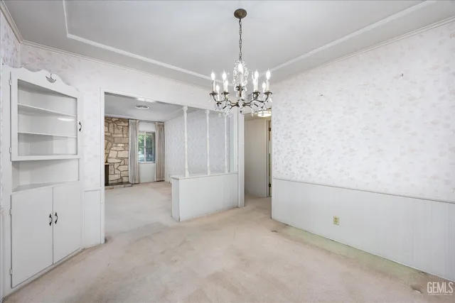 a view of an empty room with window and chandelier