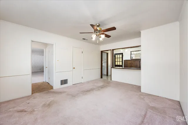 an empty room with windows and chandelier fan