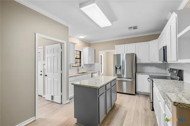 a kitchen with stainless steel appliances granite countertop a refrigerator oven a sink dishwasher and white cabinets with wooden floor