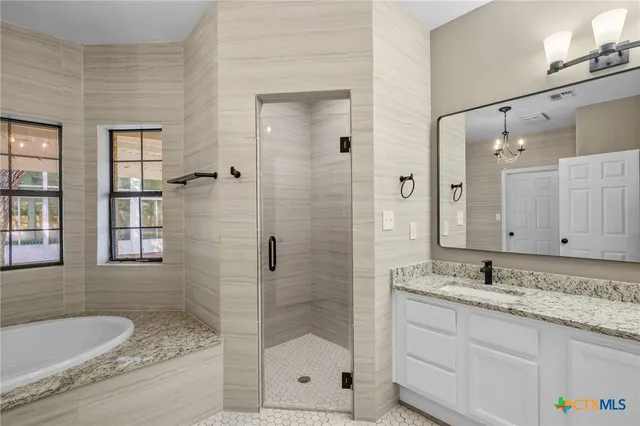a bathroom with a granite countertop double vanity sink mirror and shower