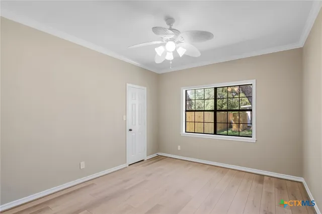 an empty room with wooden floor chandelier fan and windows
