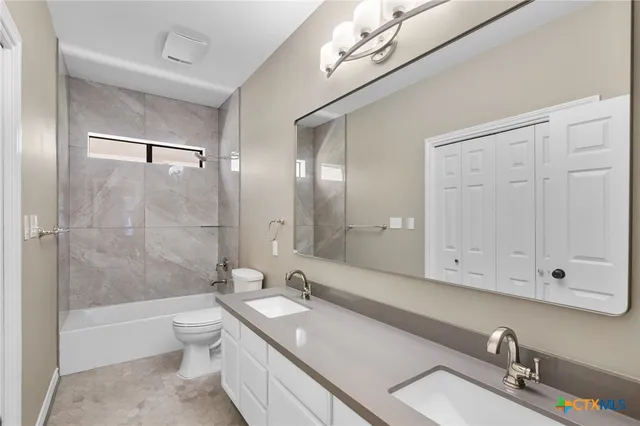 a bathroom with a granite countertop sink a toilet and shower