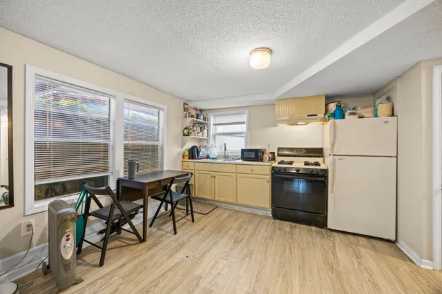 a kitchen with a refrigerator a stove a dining table and chairs with wooden floor