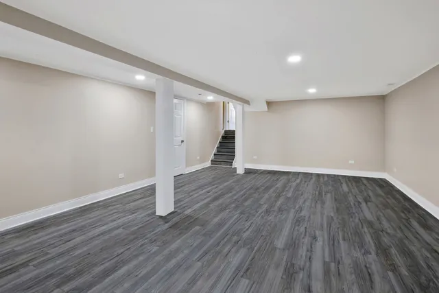a view of an empty room with wooden floor and white walls