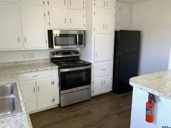 a kitchen with stainless steel appliances white cabinets and wooden floors