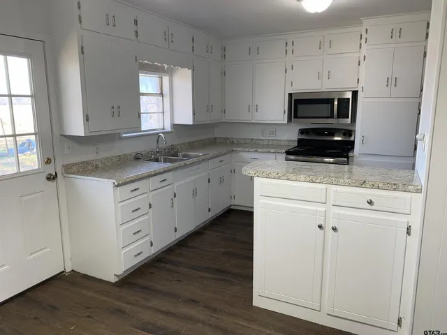 a kitchen with granite countertop white cabinets white stainless steel appliances and a sink
