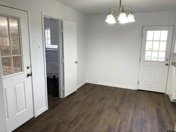 a view of empty room with wooden floor and chandelier