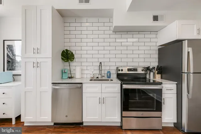 a kitchen with cabinets stainless steel appliances and wooden floor