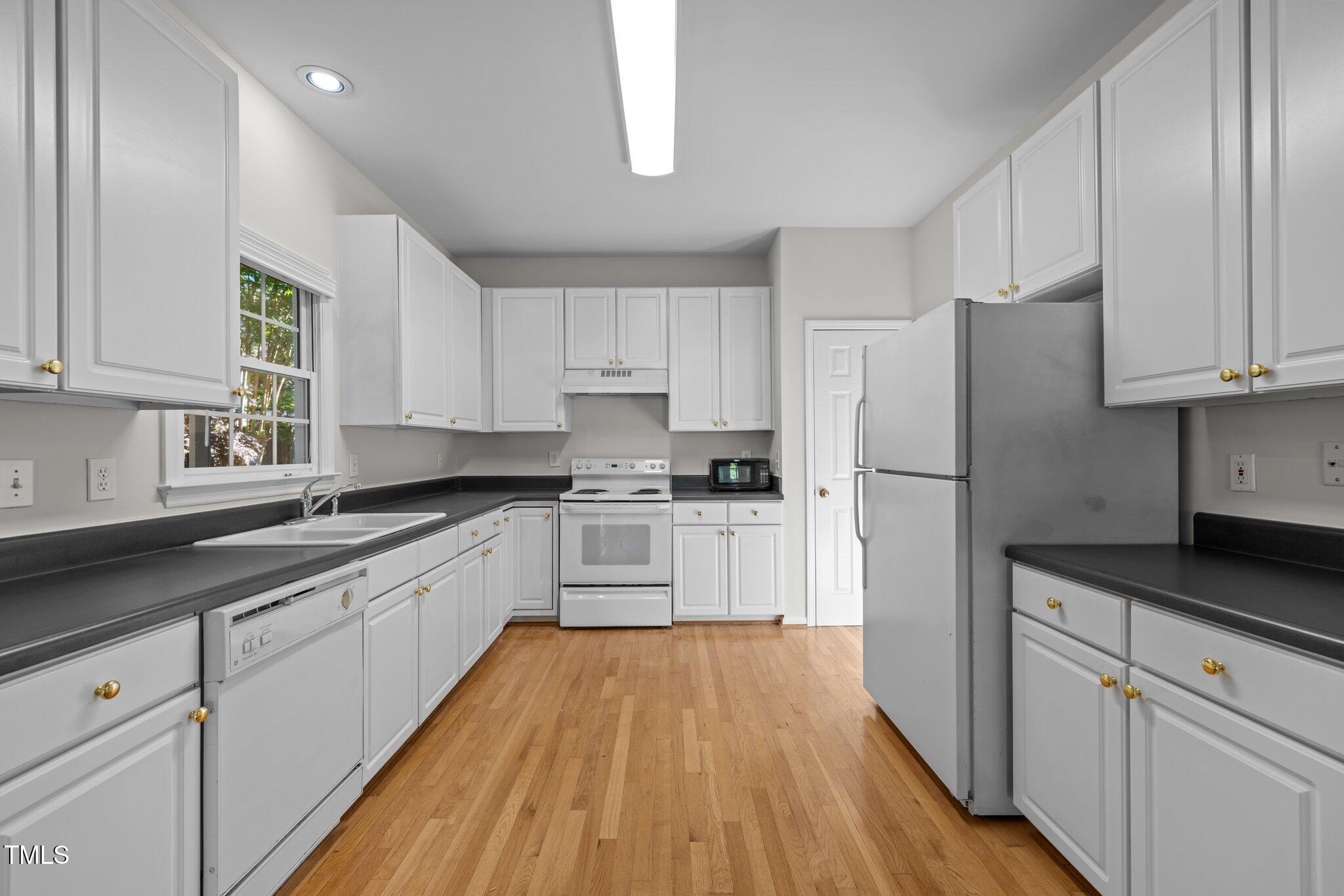 2309 Clerestory Place Raleigh, NC 27615 - Photo 12 of 37 a kitchen with granite countertop white cabinets and white appliances