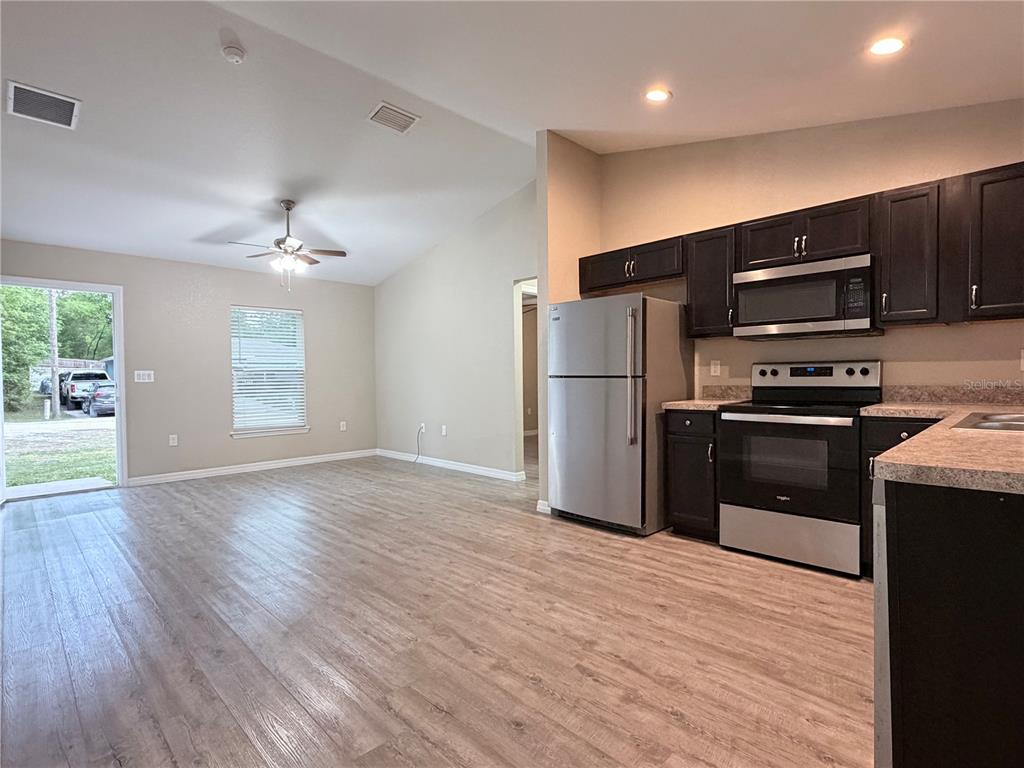 14445 Southwest 22nd Place Ocala, FL 34481 - Photo 3 of 11 a kitchen with granite countertop a refrigerator and a stove top oven