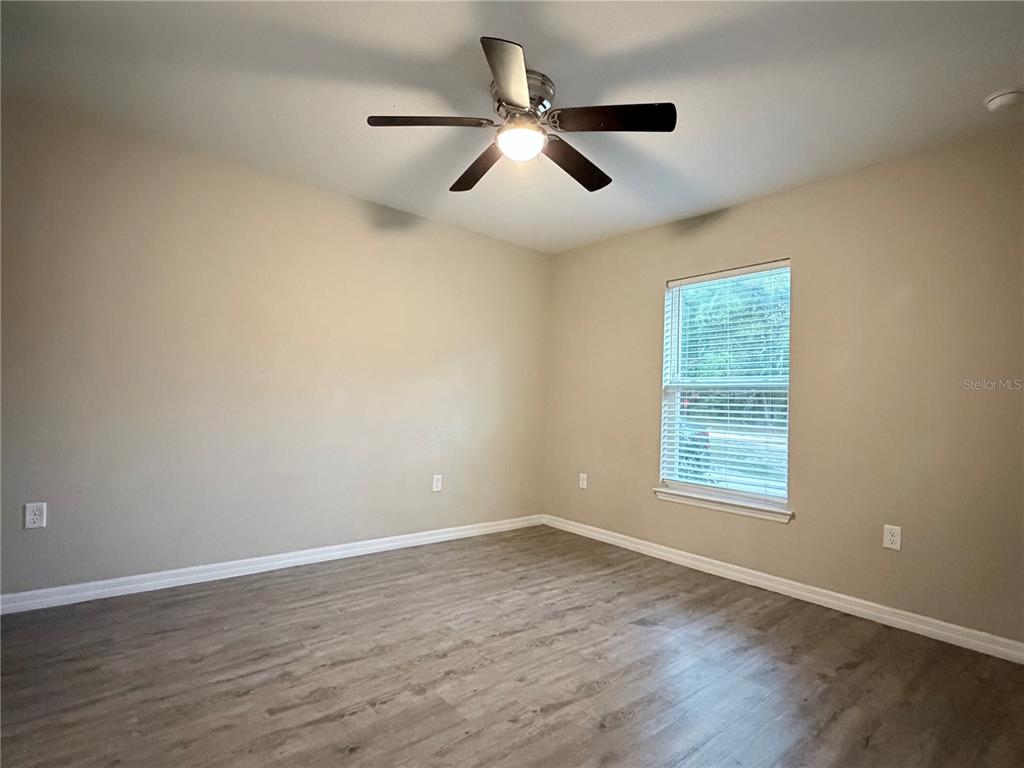 14445 Southwest 22nd Place Ocala, FL 34481 - Photo 7 of 11 an empty room with wooden floor fan and windows
