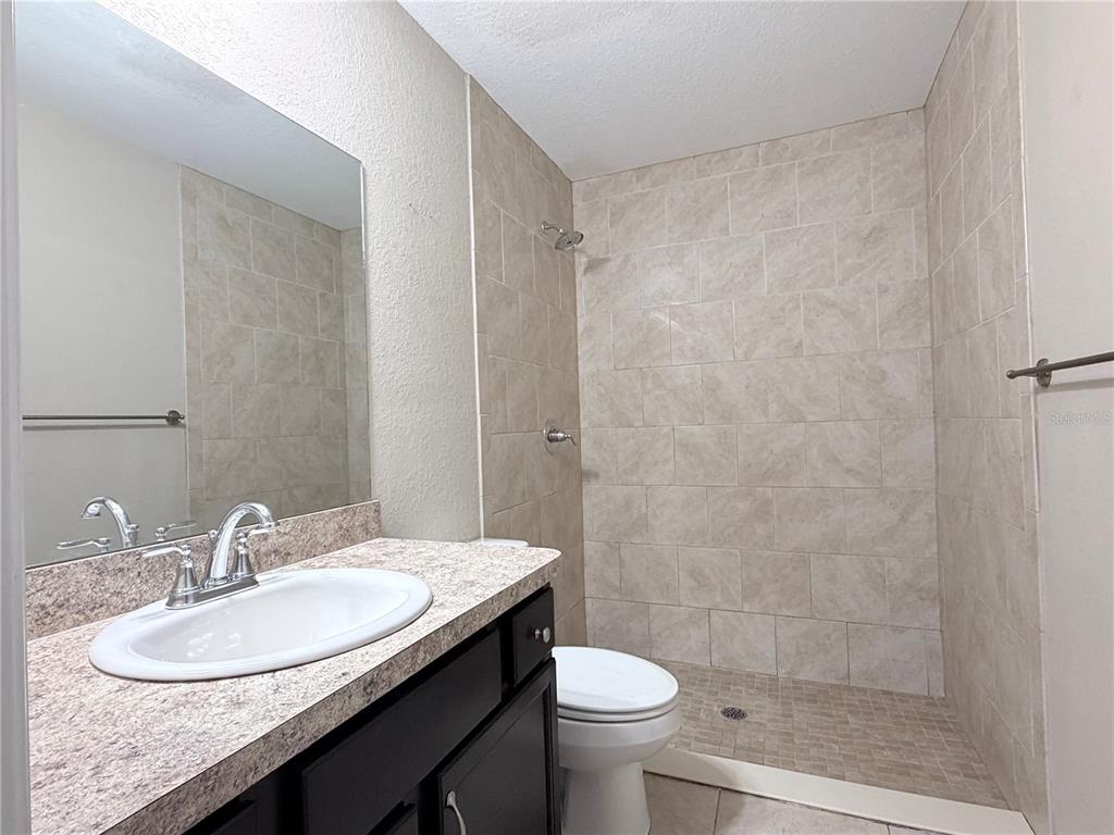 14445 Southwest 22nd Place Ocala, FL 34481 - Photo 8 of 11 a bathroom with a granite countertop sink a toilet a mirror and shower