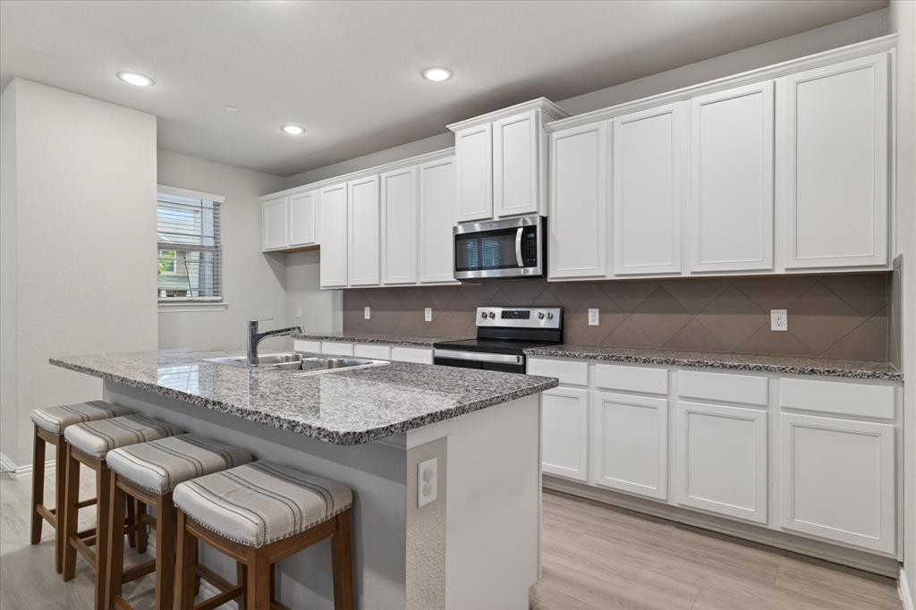 2200 Davenport Drive Denton, TX 76207 - Photo 7 of 23 a kitchen with stainless steel appliances granite countertop a sink a stove a microwave a refrigerator and white cabinets