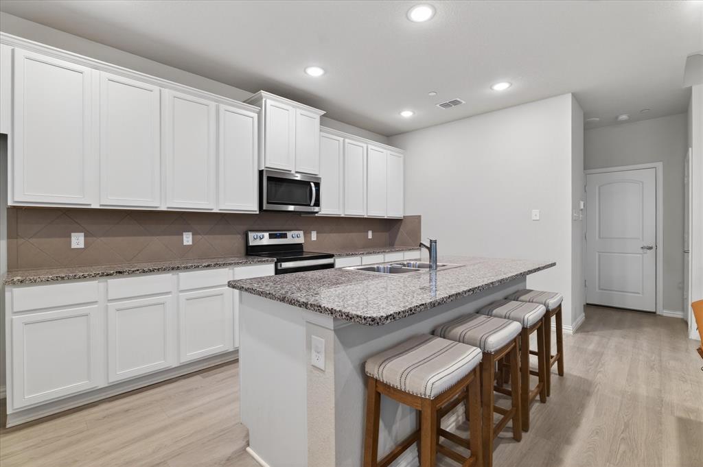 2200 Davenport Drive Denton, TX 76207 - Photo 10 of 23 a kitchen with granite countertop a sink and white cabinets