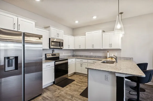 a kitchen with granite countertop a refrigerator a sink a stove a microwave and island