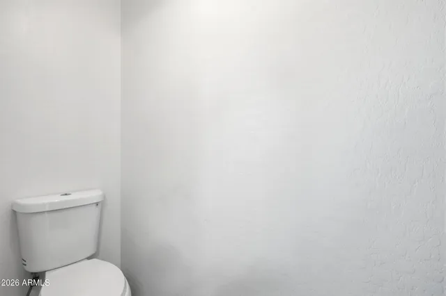a white toilet sitting next to a white wall