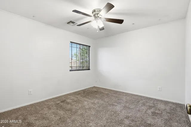 an empty room with windows and fan