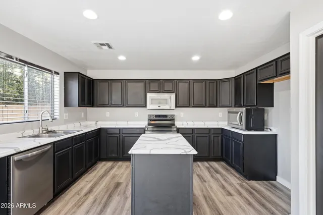 a kitchen with kitchen island granite countertop a sink stove and refrigerator