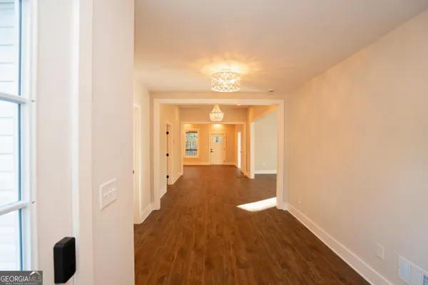 a view of an empty room with window and wooden floor