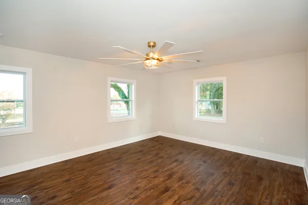 an empty room with wooden floor closet and fan