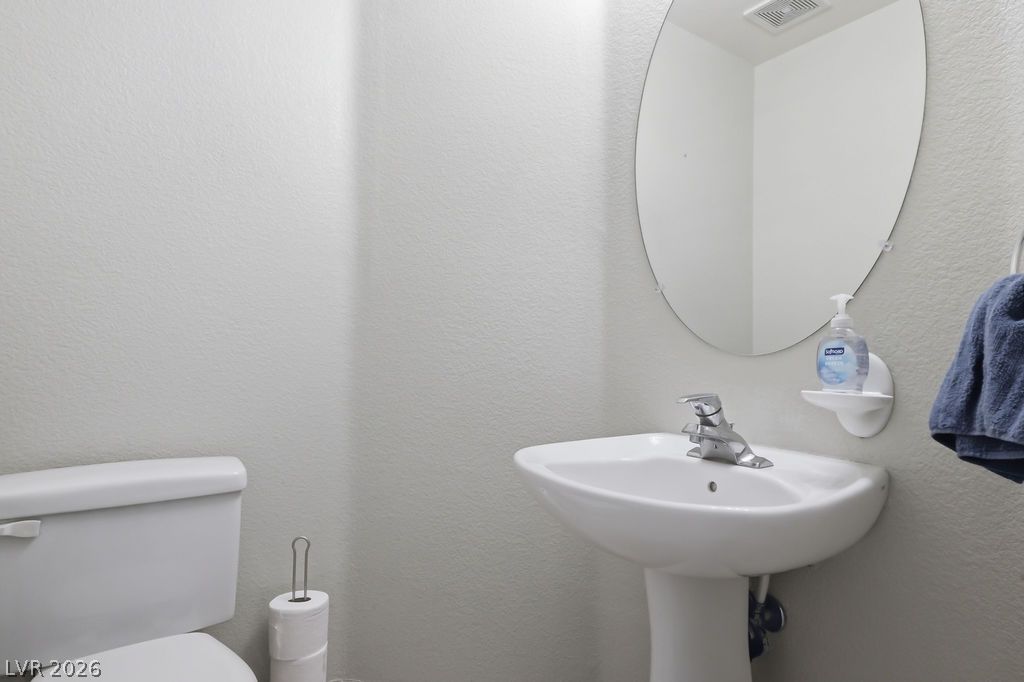 754 Solitude Point Avenue Henderson, NV 89012 - Photo 20 of 38 A well-appointed half-bathroom featuring a sleek pedestal sink and convenient commode.
