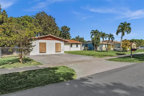 a view of a yard in front of a house with large windows