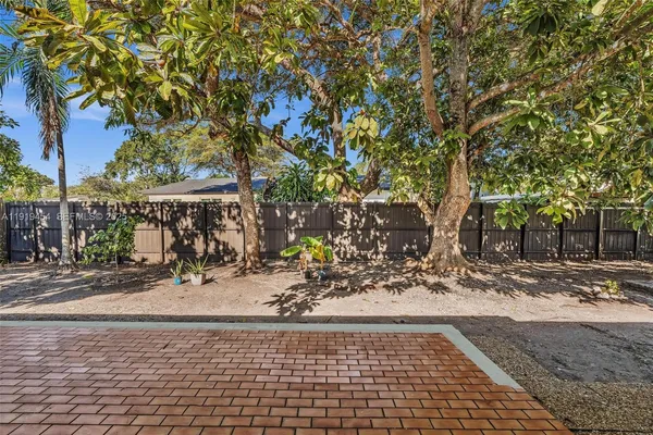 a view of a backyard with large trees and wooden fence