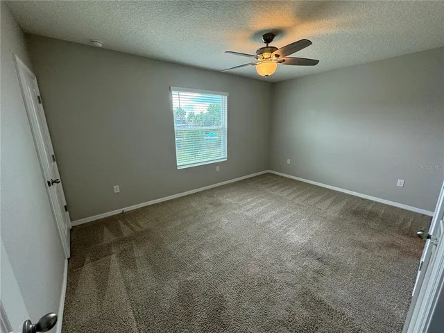 an empty room with windows and fan