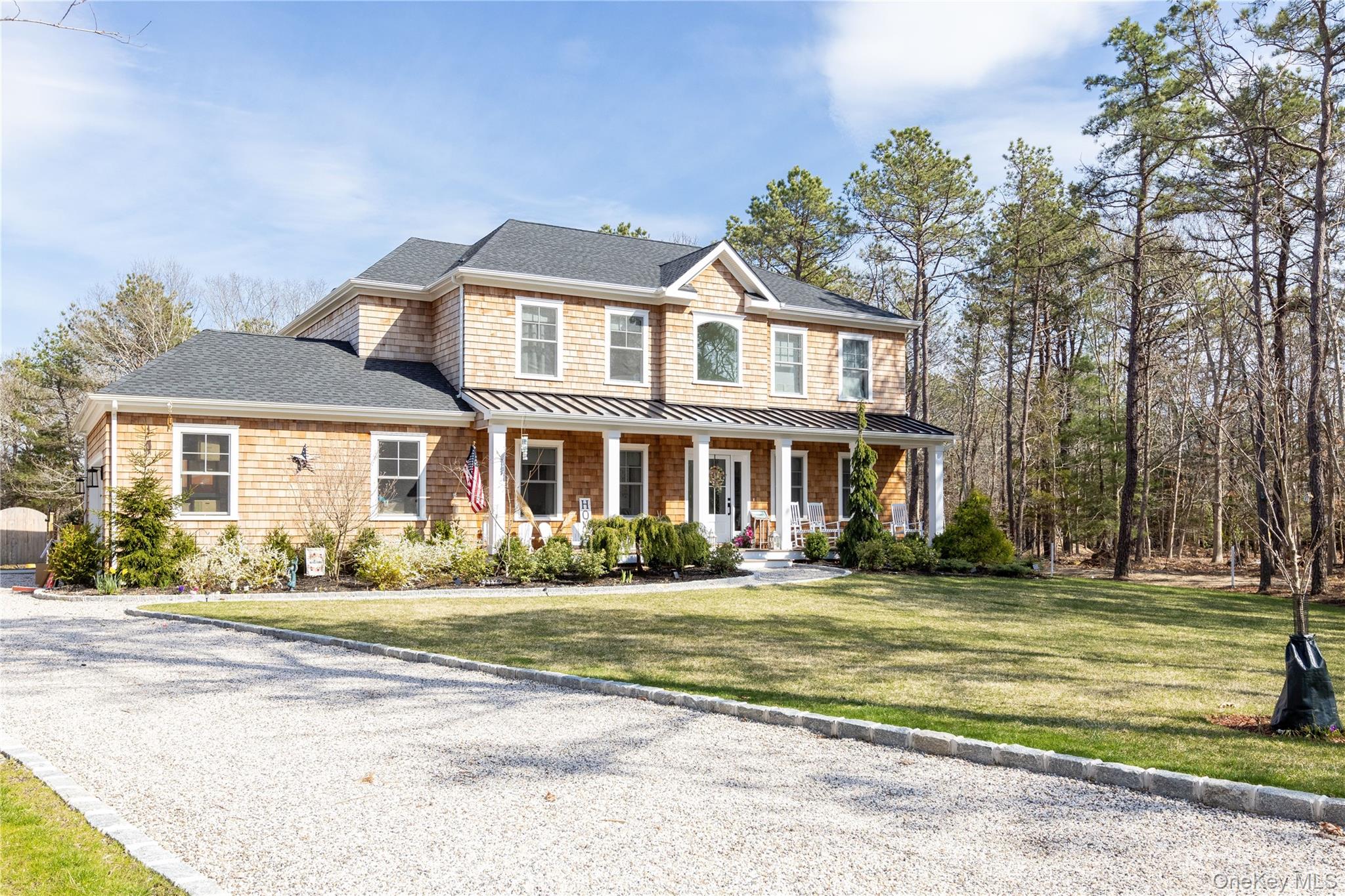 View of front of home featuring a standing seam roof, covered porch, a shingled roof, a metal roof, and a front lawn