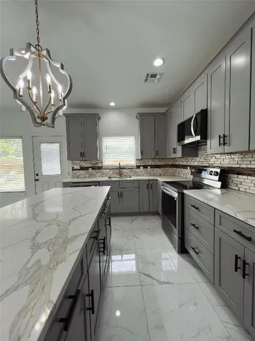 a kitchen with stainless steel appliances granite countertop a sink dishwasher stove top oven and cabinets