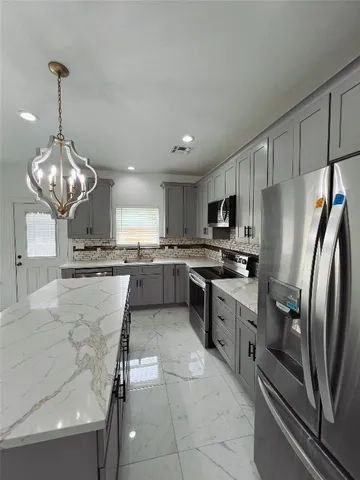 a large kitchen with stainless steel appliances kitchen island granite countertop a sink refrigerator and cabinets