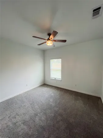 an empty room with a ceiling fan and window
