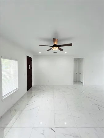 an empty room with a ceiling fan and window