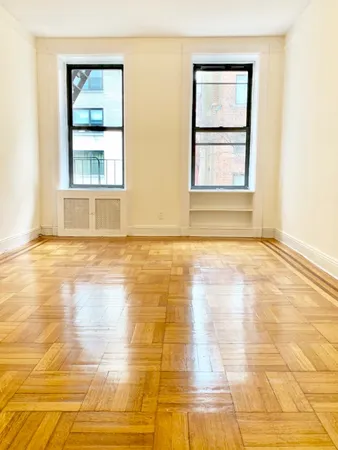 a view of an empty room with window and wooden floor