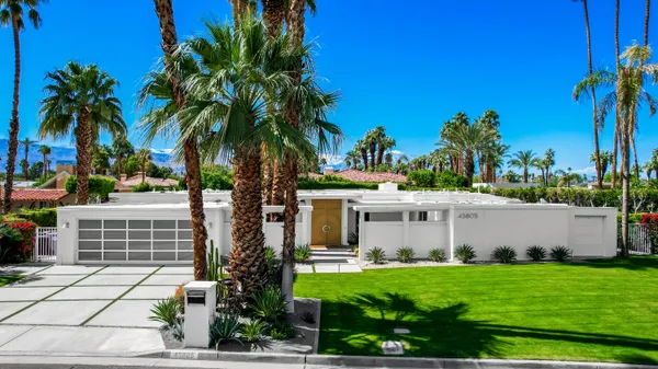 a front view of a house with garden and trees