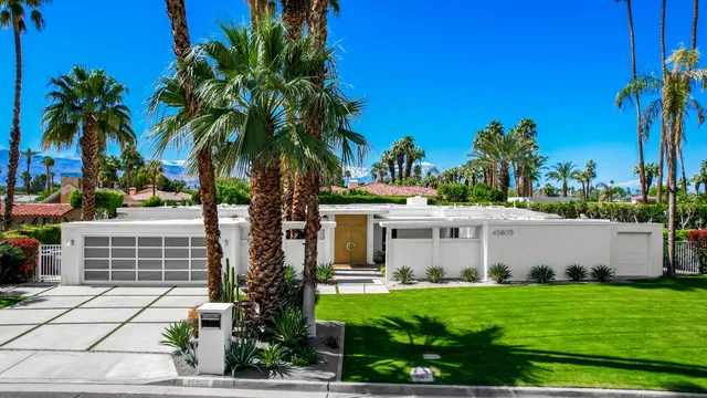 a front view of a house with garden and trees