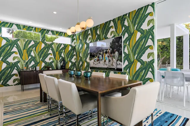 a view of a dining room with furniture one side kitchen view and wooden floor