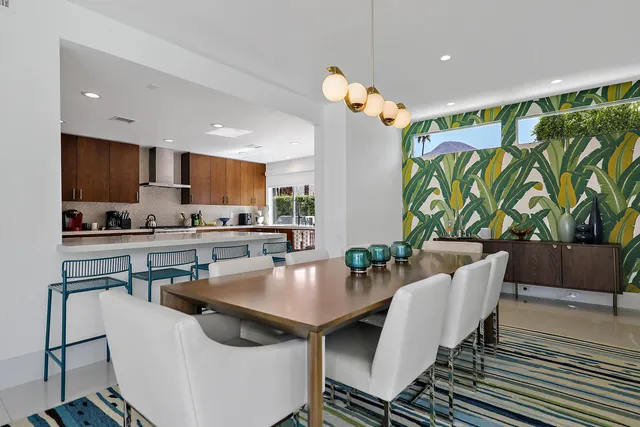 a kitchen with stainless steel appliances a dining table chairs and a refrigerator