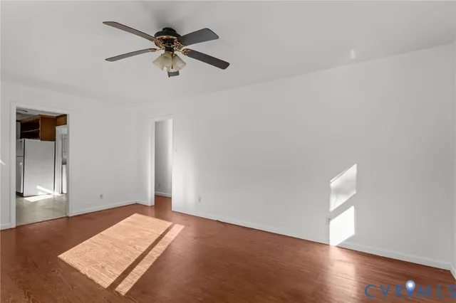 an empty room with wooden floor chandelier fan and windows
