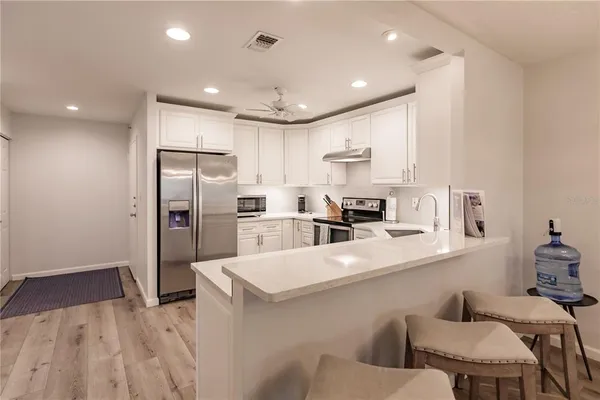 a kitchen with stainless steel appliances kitchen island a refrigerator sink and cabinets