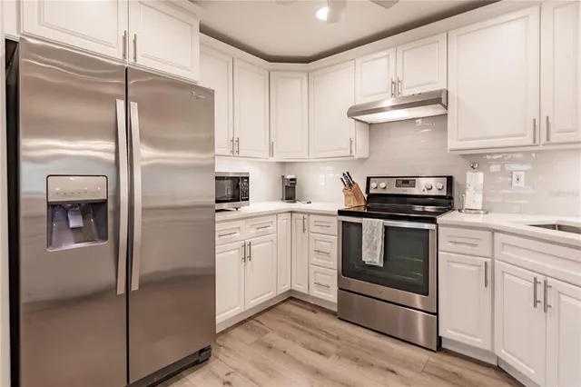 a kitchen with white cabinets and stainless steel appliances