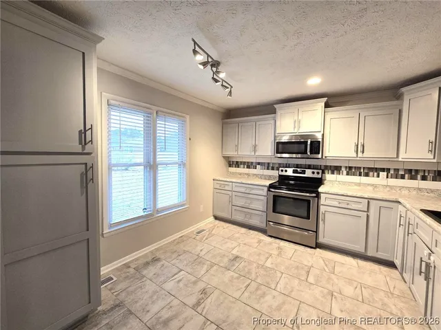 a kitchen with stainless steel appliances granite countertop a refrigerator a sink a stove a microwave and cabinets