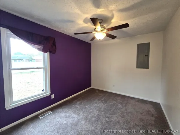 an empty room with windows and fan
