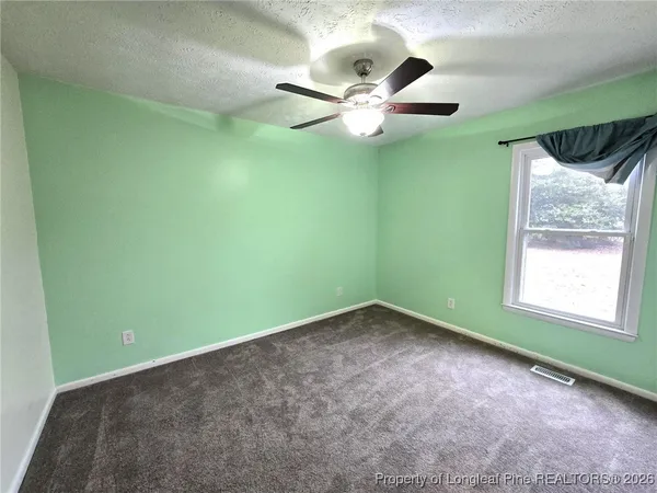 an empty room with a ceiling fan and a window