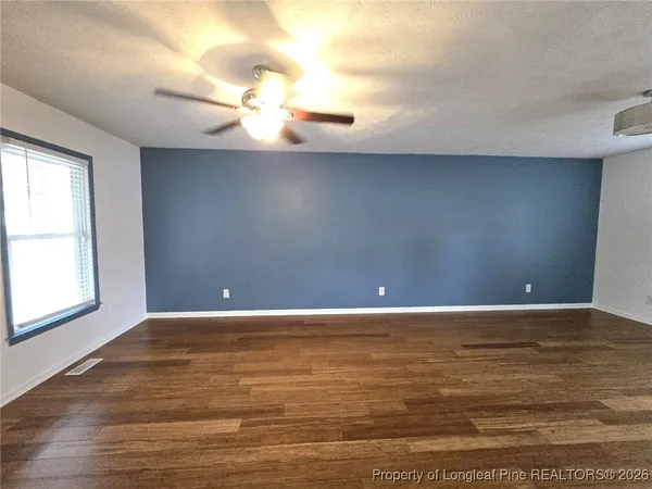 a view of an empty room with window and wooden floor